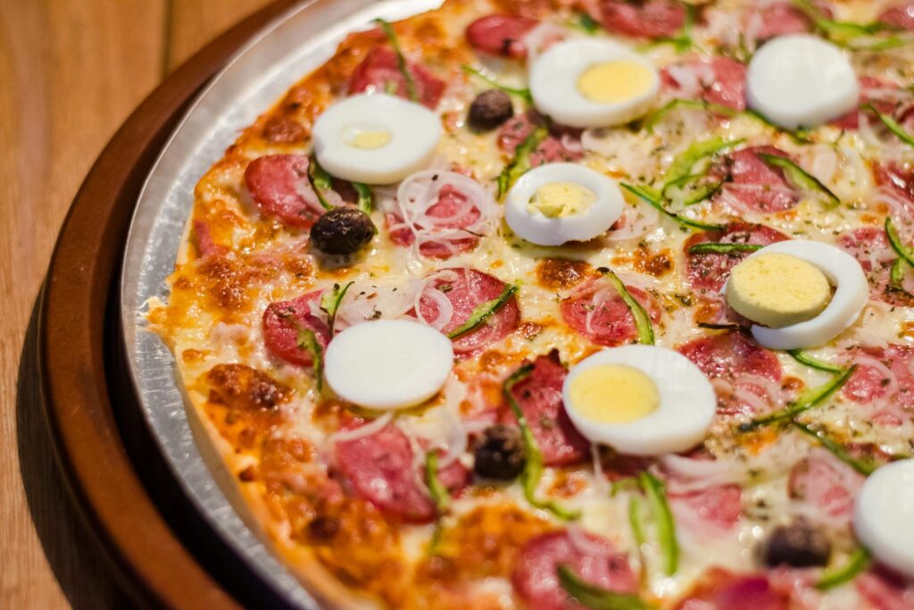 Savor a close-up of pizza topped with pepperoni, eggs, and fresh vegetables.